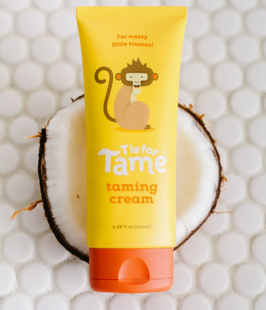 Yellow taming cream tube printed with a monkey, resting on a halved coconut