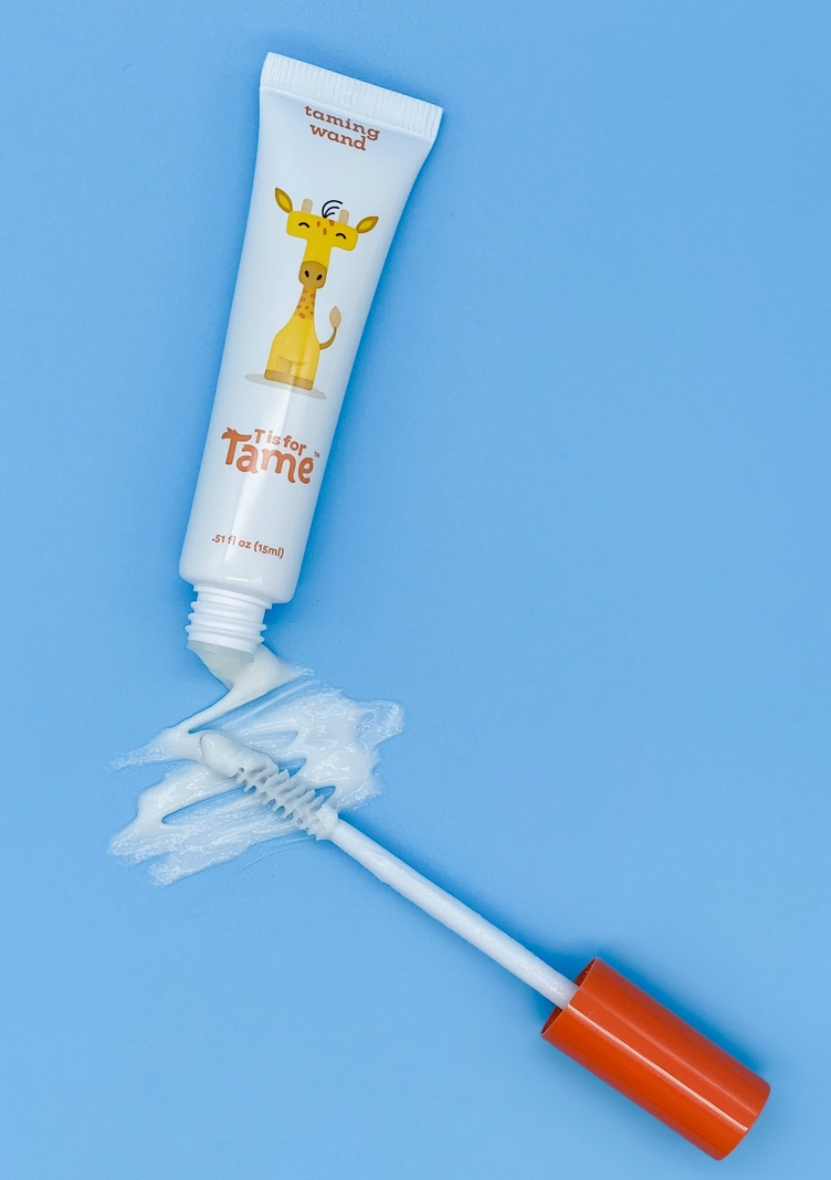 The taming wand squeezed onto its brush applicator against a blue ground